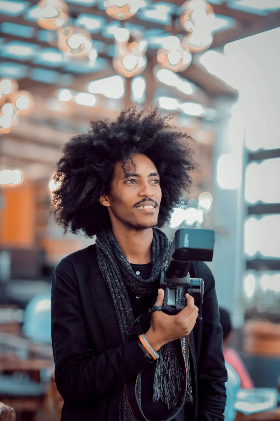 A young creator holding a camera in a busy café